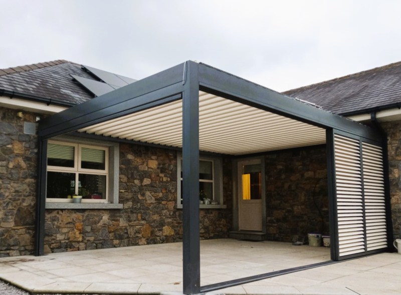 Bioclimatic louvred pergola on a stone-clad house