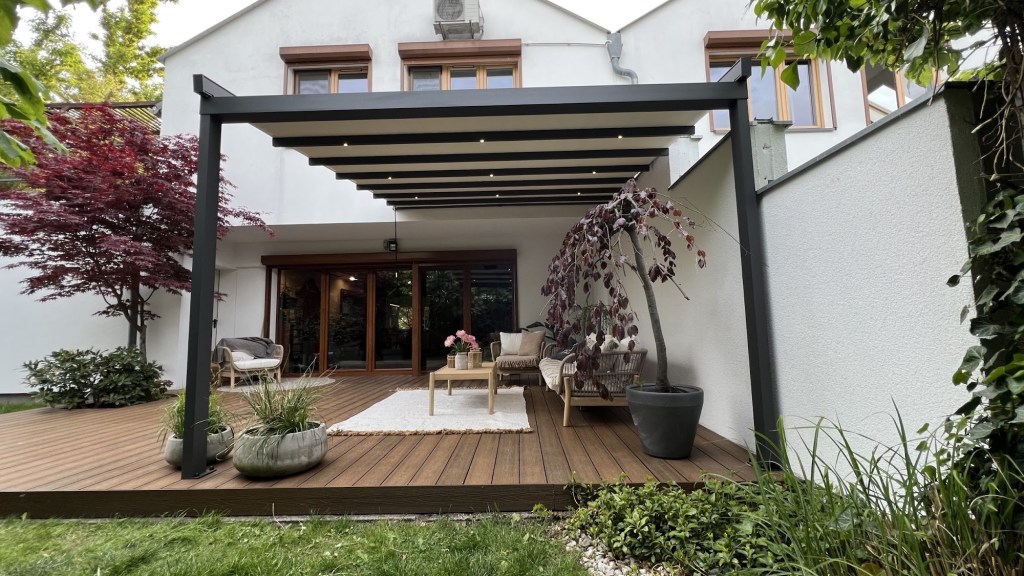 Retractable pergola on a timber deck beside a white house