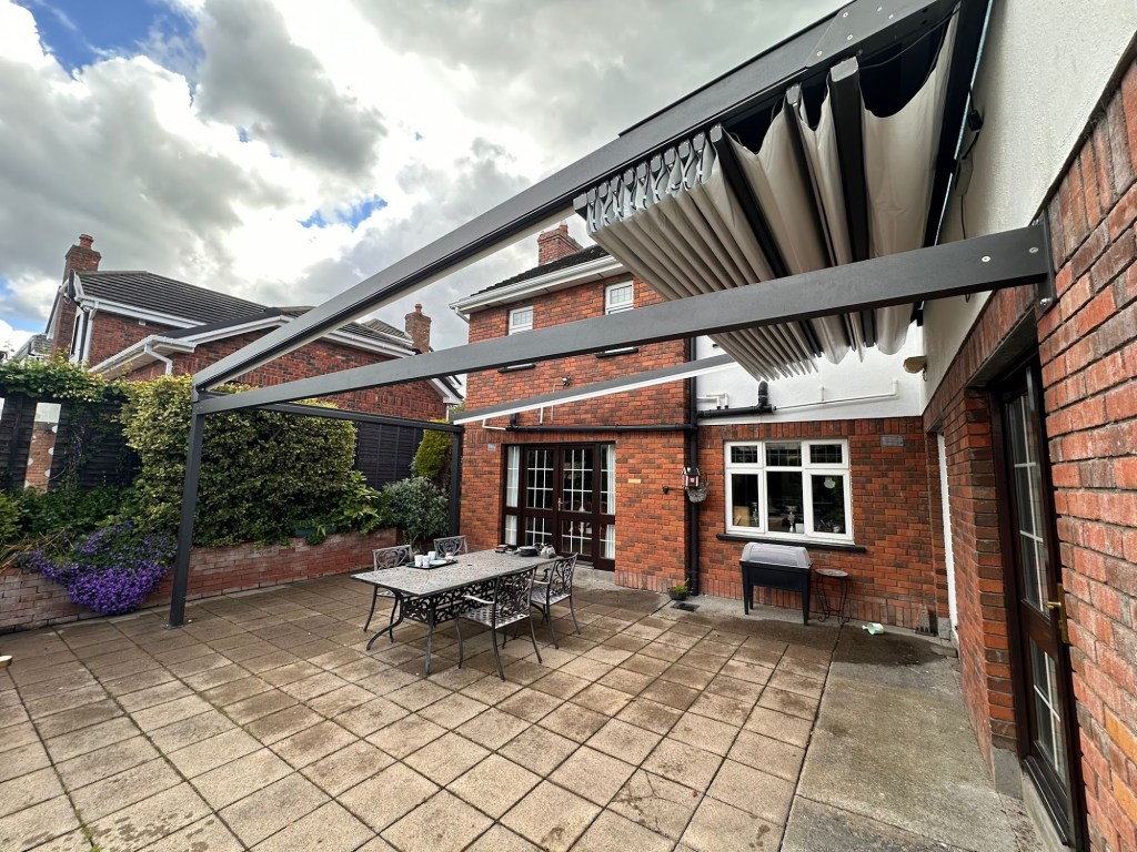 Retractable pergola over a paved patio by a brick house