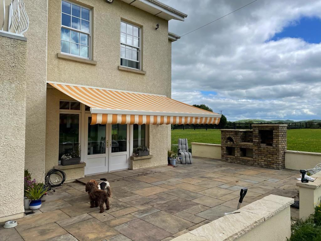 Striped retractable awning shading a house patio in Ireland