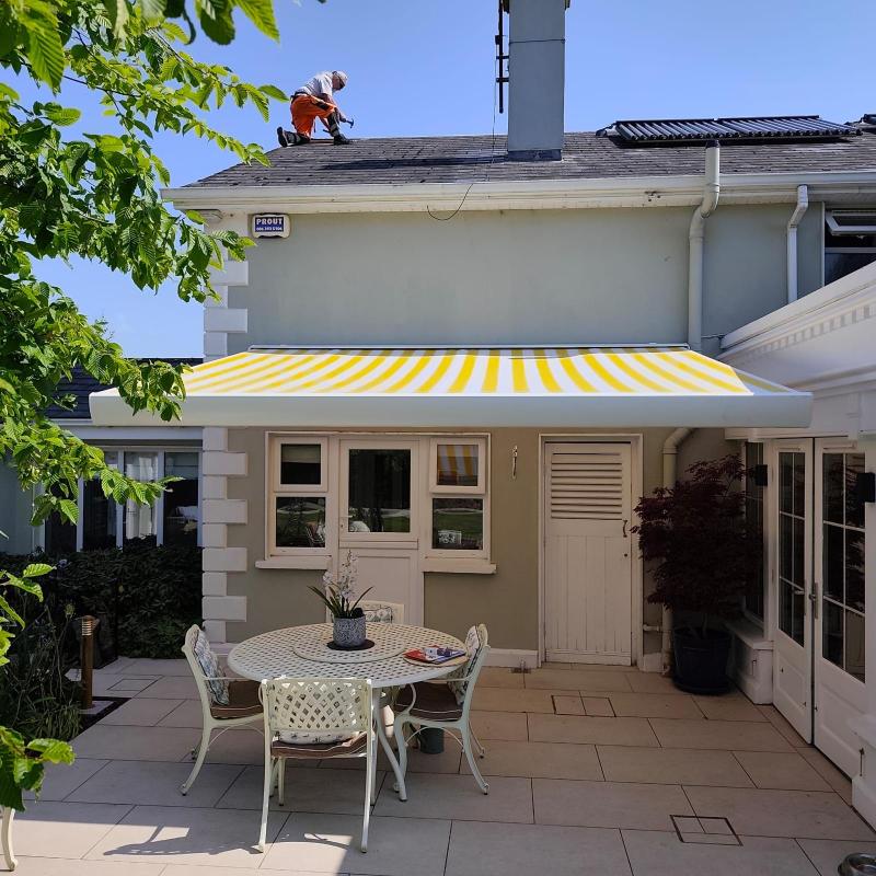 Yellow and white striped retractable patio awning on a family home in Ireland